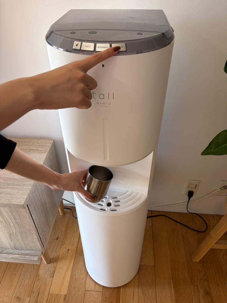 ボタンを押してカップに水を注ぐところ